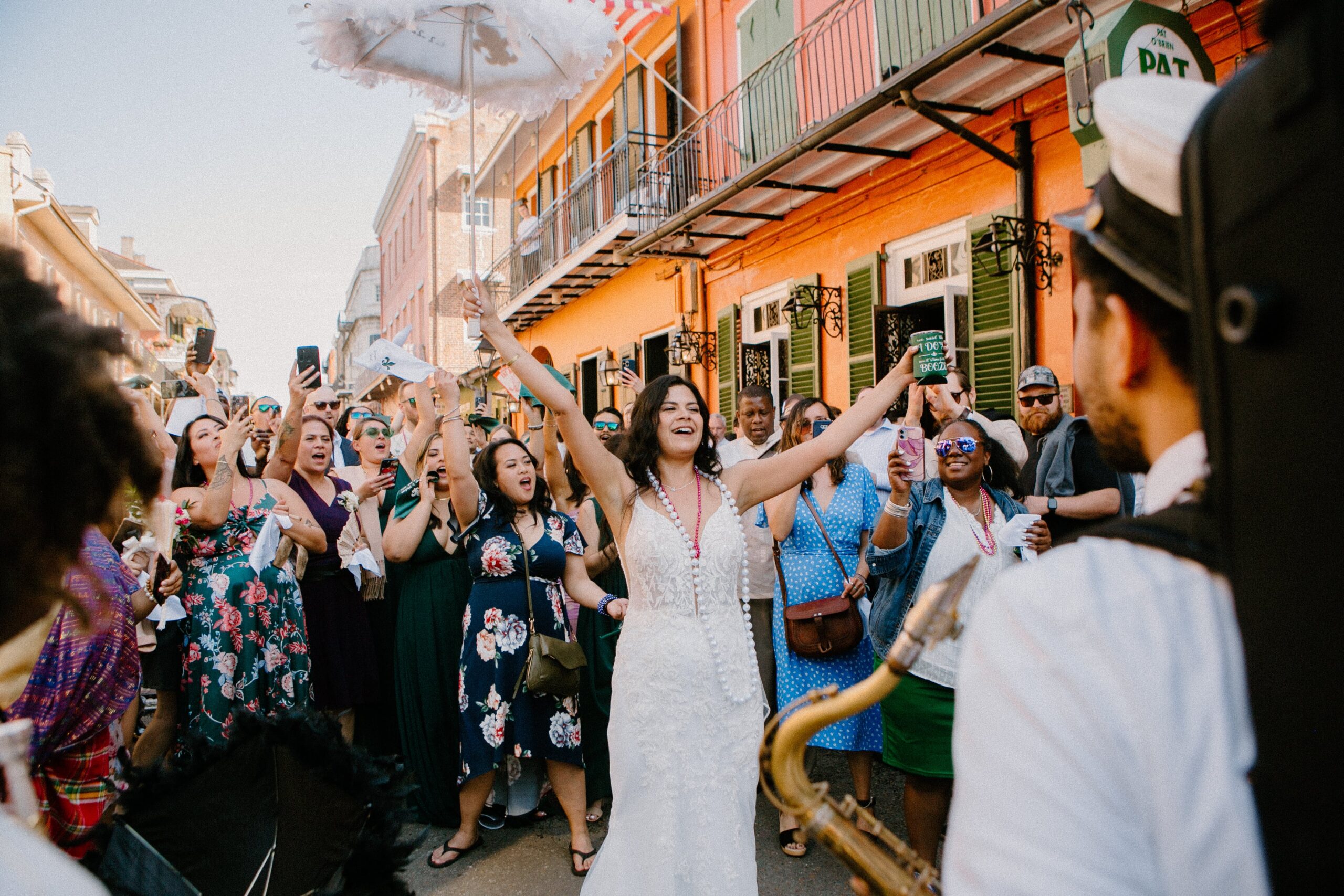 Bride leading her second line parade through the French Quarter in New Orleans with guests and a brass band behind her