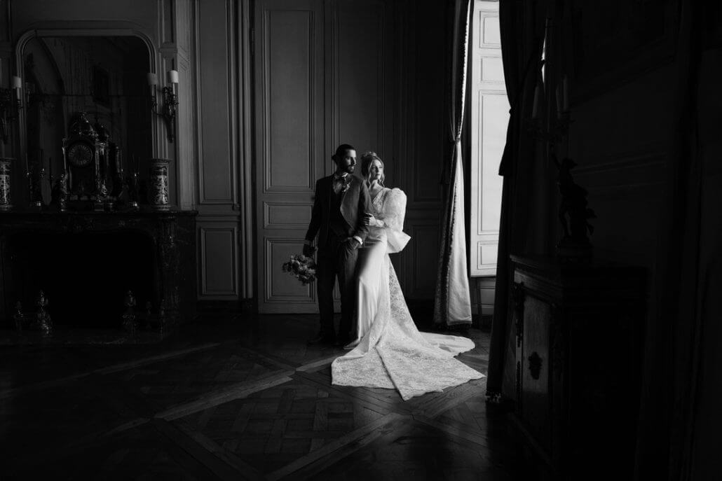 Houston wedding photography by Toast: a bride and groom stand together in formal attire in a dimly lit, elegant room with wooden floors and ornate decor.