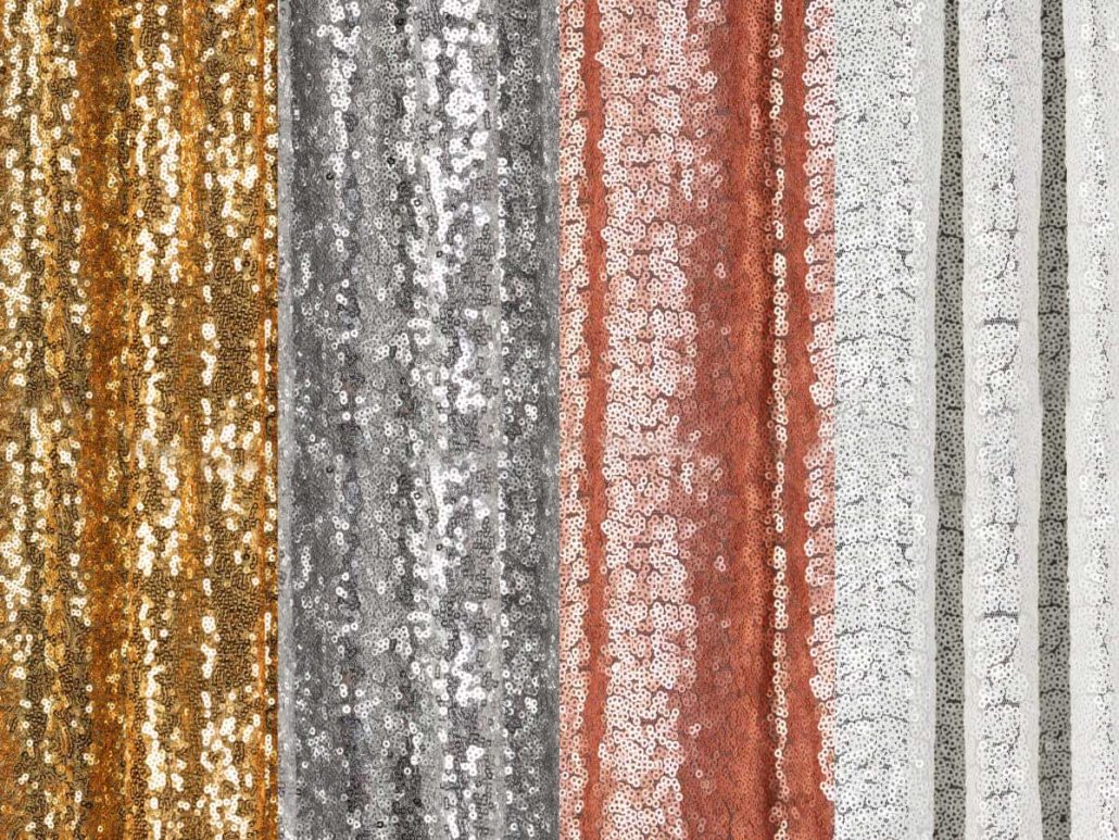photo-booth-sequin-backdrop Vertical strips of sequin fabric in gold, silver, rose gold, and white colors, arranged side by side.