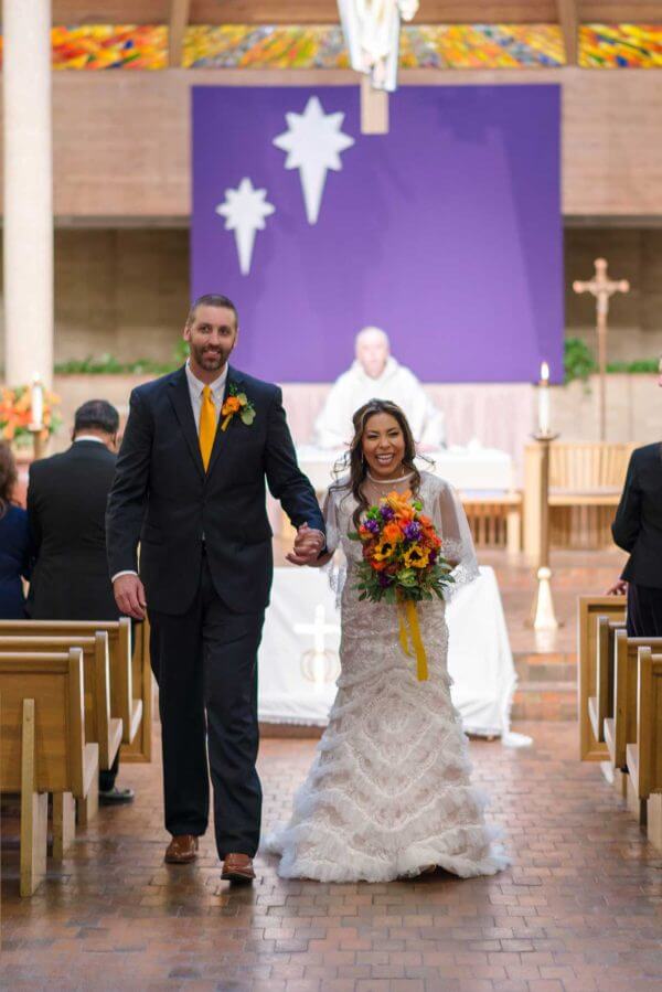 Austin wedding photography by Toast: bride and groom walk back up the church aisle after their ceremony.