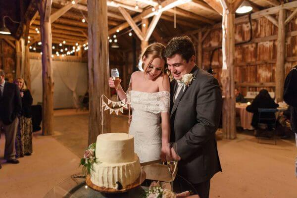 Austin wedding photography by Toast: bride and groom cut a white cake at a rustic barn reception.