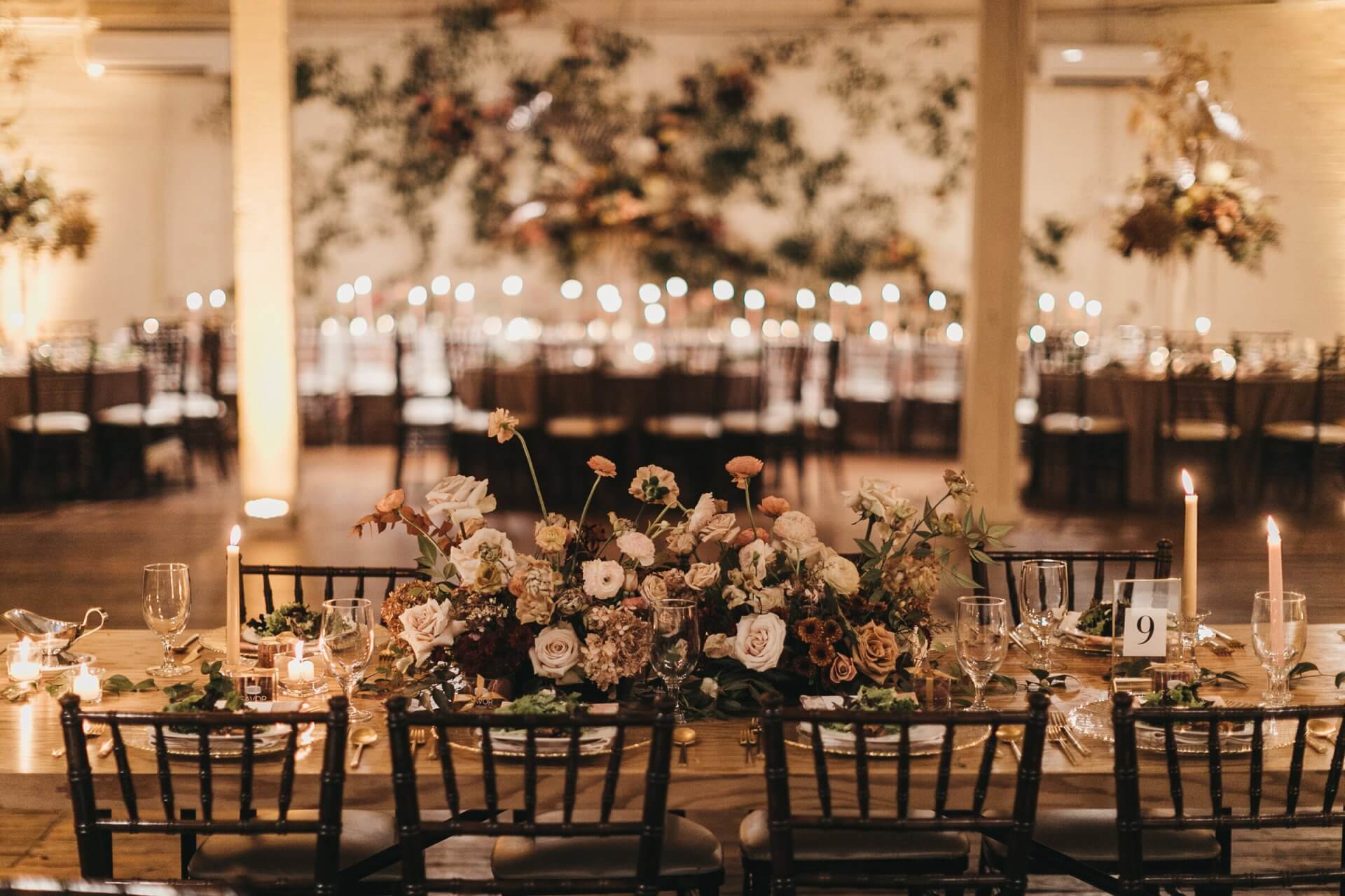 Elegant dining table set for an event with floral centerpieces, candles, glassware, and place settings in a warmly lit room—perfect inspiration for wedding venues in Fort Worth.