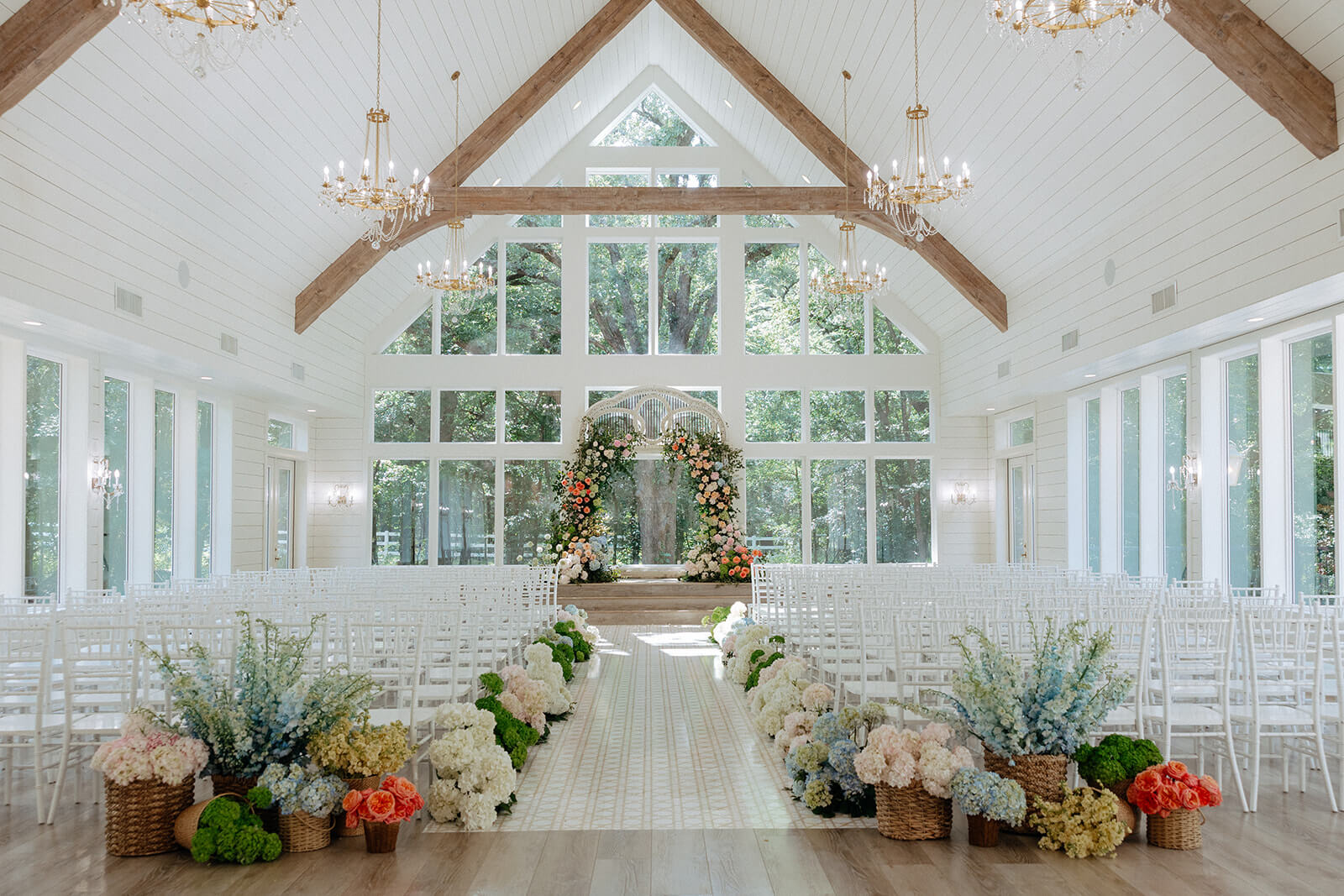 A bright, spacious wedding chapel among the top wedding venues in Fort Worth, featuring rows of white chairs, elegant floral arrangements along the aisle, and large windows flooding the space with natural light.