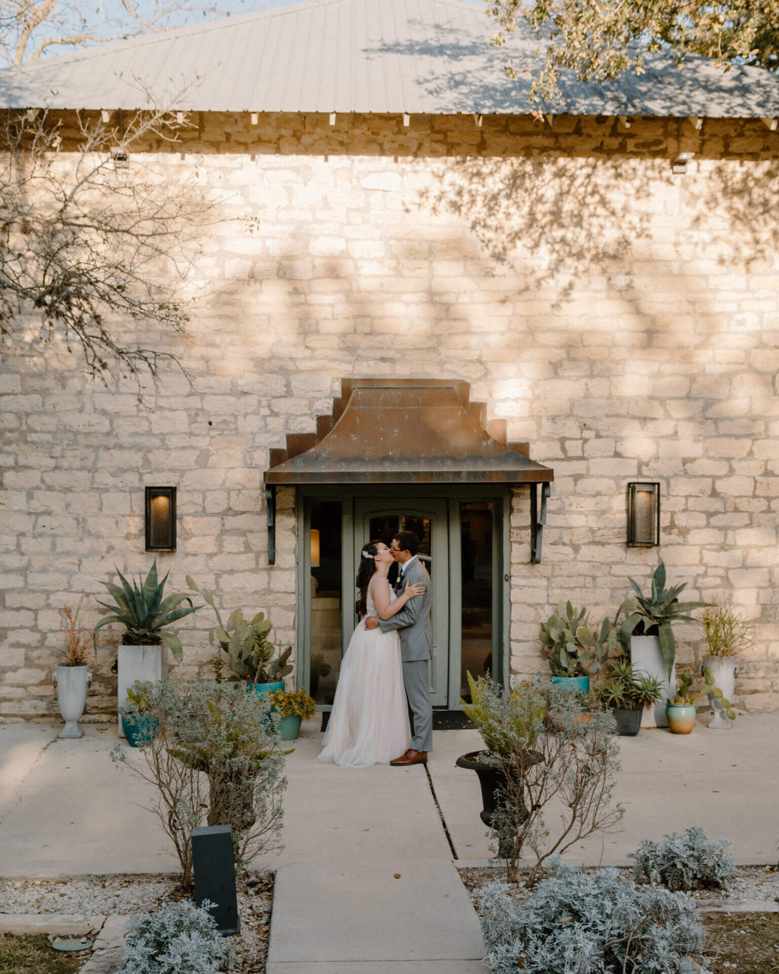Bride and groom at the limestone front entrance of Stonehouse Villa, Driftwood TX wedding venue